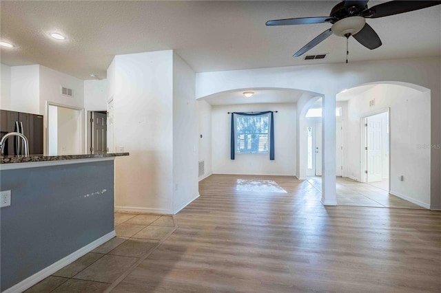 interior space with ceiling fan, sink, stainless steel fridge, a textured ceiling, and light wood-type flooring