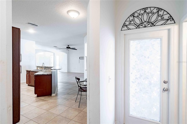 interior space featuring a textured ceiling, ceiling fan, light tile patterned floors, and sink