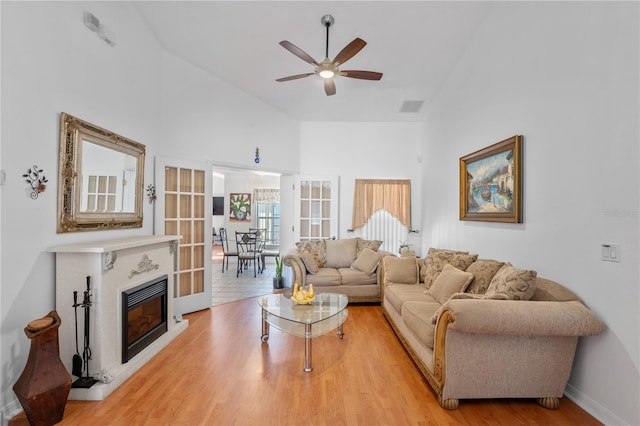 living room featuring high vaulted ceiling, light wood-type flooring, and ceiling fan