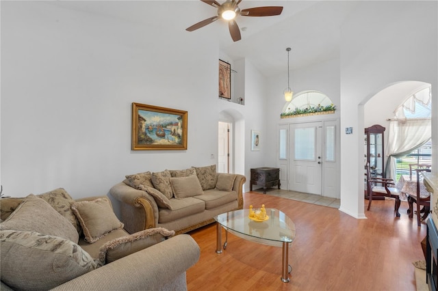 living room featuring light hardwood / wood-style flooring, high vaulted ceiling, and ceiling fan