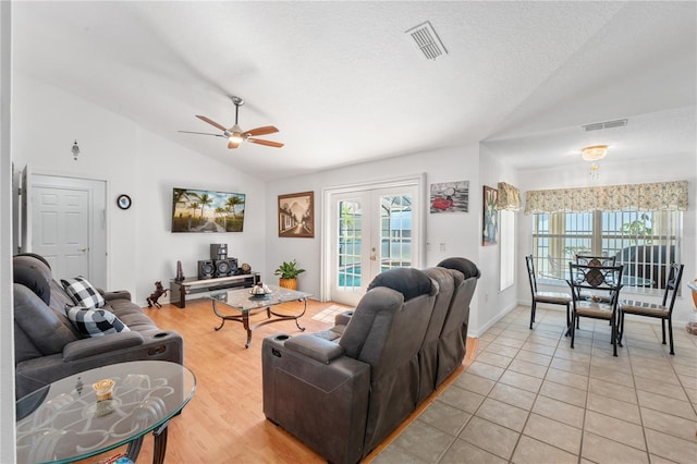 living room featuring ceiling fan, light tile patterned floors, a textured ceiling, vaulted ceiling, and french doors