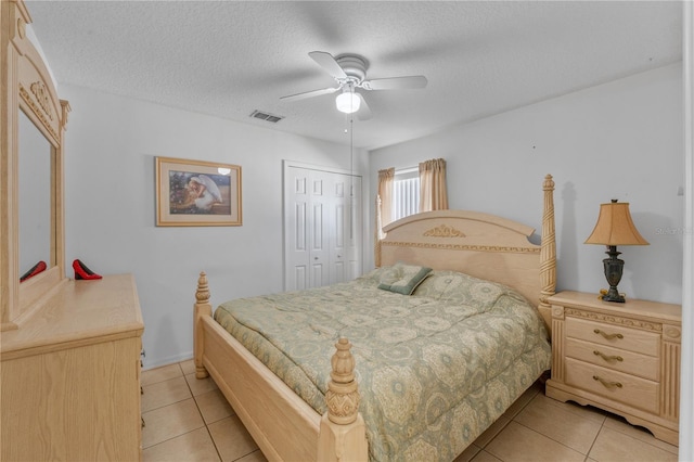 tiled bedroom with a closet, ceiling fan, and a textured ceiling