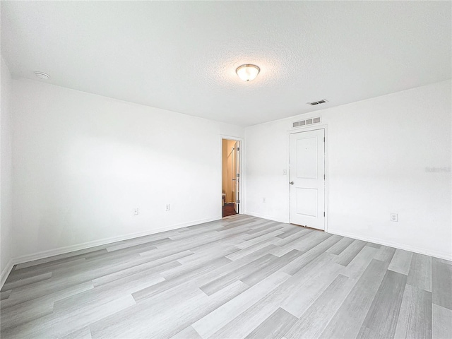 empty room with a textured ceiling and light wood-type flooring