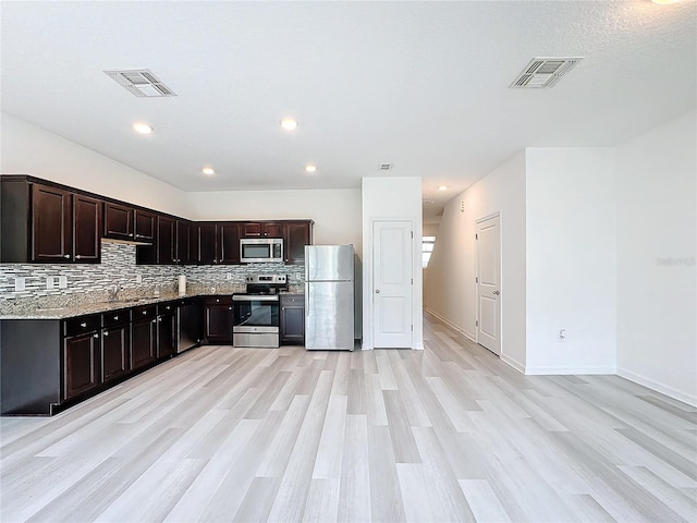 kitchen featuring tasteful backsplash, dark brown cabinets, appliances with stainless steel finishes, light hardwood / wood-style flooring, and light stone counters