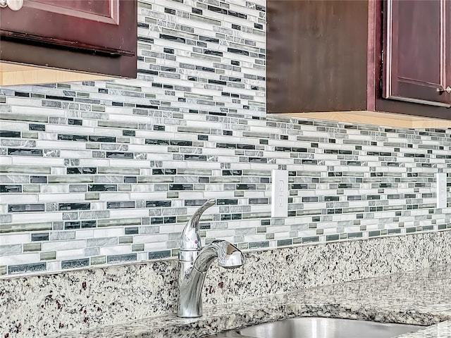 details with sink, light stone counters, and tasteful backsplash