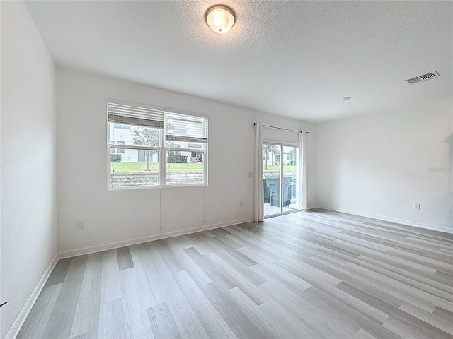 unfurnished room featuring light hardwood / wood-style flooring and a textured ceiling