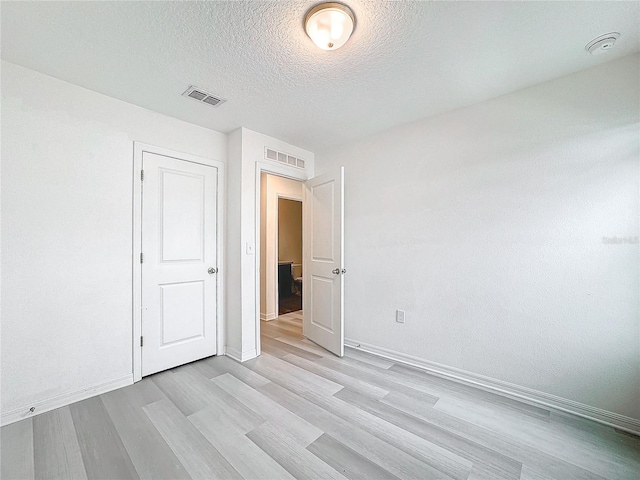 unfurnished room featuring light hardwood / wood-style floors and a textured ceiling