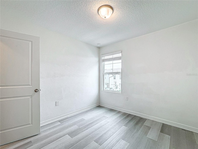 spare room with a textured ceiling and light wood-type flooring