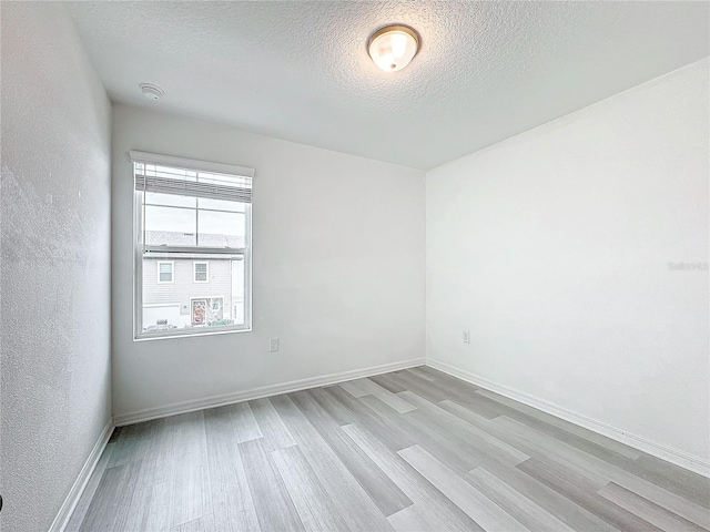 empty room with light hardwood / wood-style floors and a textured ceiling