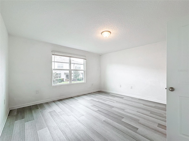 unfurnished room with light hardwood / wood-style floors and a textured ceiling