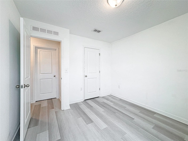 unfurnished bedroom featuring a textured ceiling and light wood-type flooring