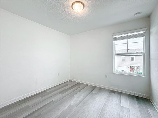 spare room with a textured ceiling and light hardwood / wood-style flooring