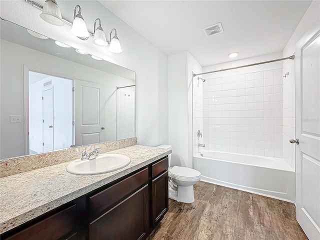 full bathroom featuring vanity, toilet, tiled shower / bath combo, and hardwood / wood-style floors