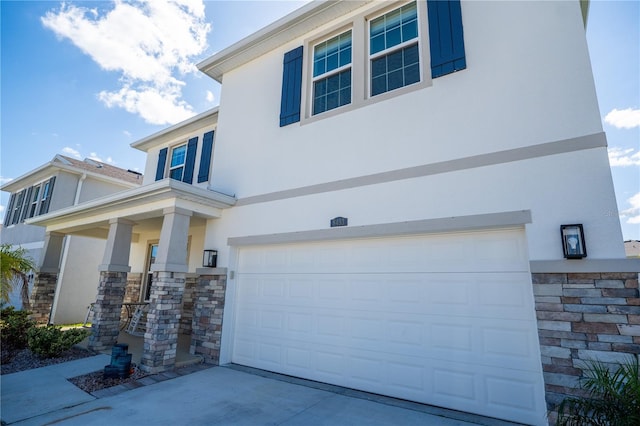 view of front of home with stucco siding, stone siding, a garage, and concrete driveway