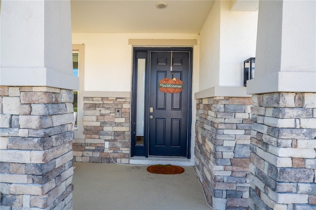 view of exterior entry with stone siding and stucco siding