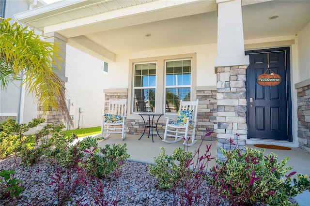 view of exterior entry featuring covered porch and stone siding