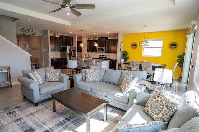 living area with recessed lighting, baseboards, and ceiling fan with notable chandelier