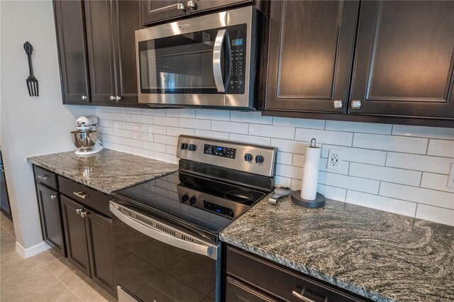 kitchen with dark brown cabinetry, stainless steel appliances, dark stone counters, and tasteful backsplash