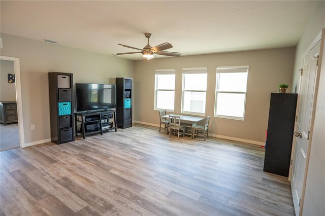 living area with light wood finished floors, baseboards, and a ceiling fan