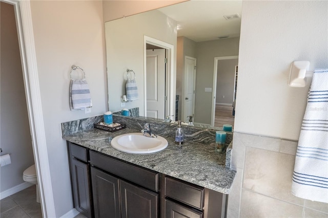 bathroom with toilet, tile patterned flooring, baseboards, and vanity