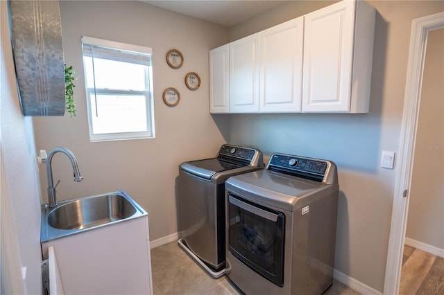 laundry room with a sink, baseboards, cabinet space, and separate washer and dryer