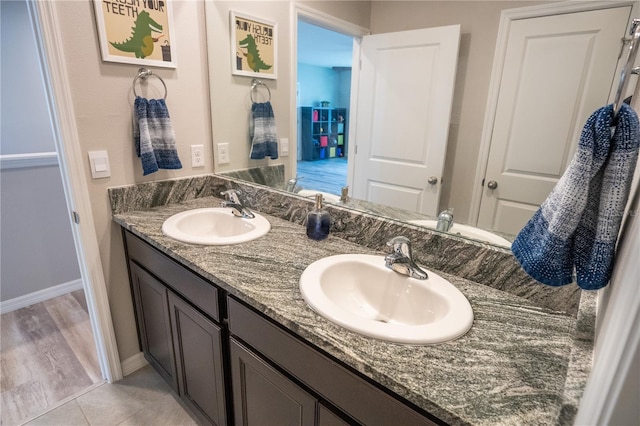 full bathroom with double vanity, baseboards, and a sink