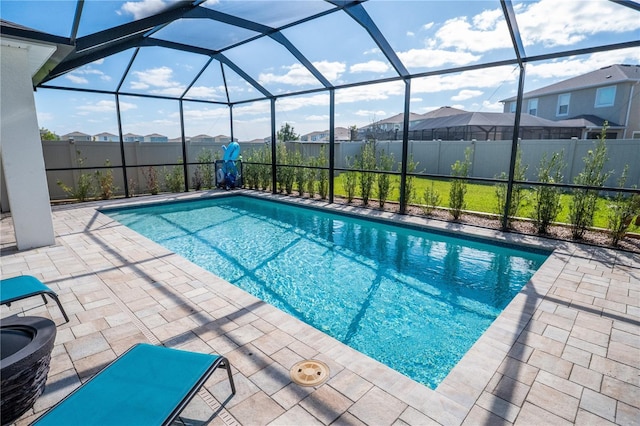 view of swimming pool featuring glass enclosure, a patio area, fence, and a residential view