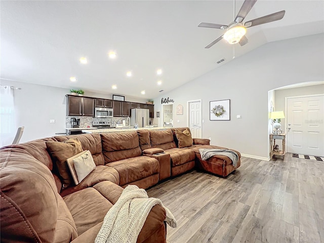 living room with ceiling fan, lofted ceiling, and light wood-type flooring