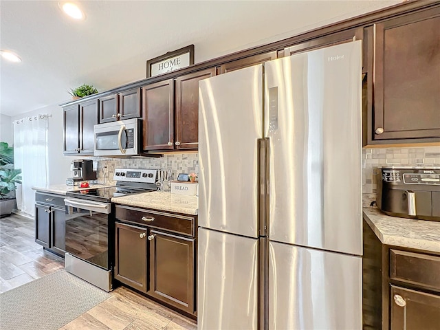 kitchen featuring appliances with stainless steel finishes, tasteful backsplash, dark brown cabinets, and light wood-type flooring