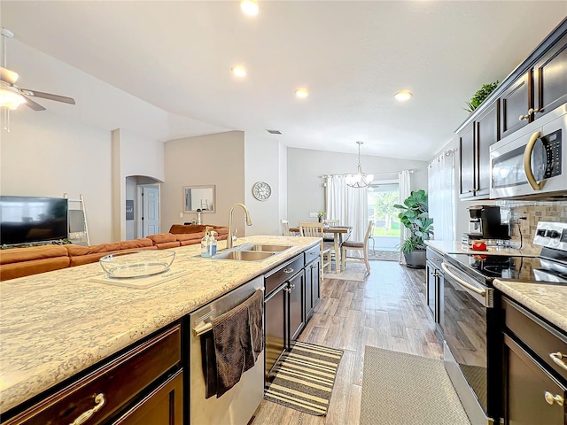 kitchen with lofted ceiling, light hardwood / wood-style flooring, stainless steel appliances, sink, and decorative light fixtures