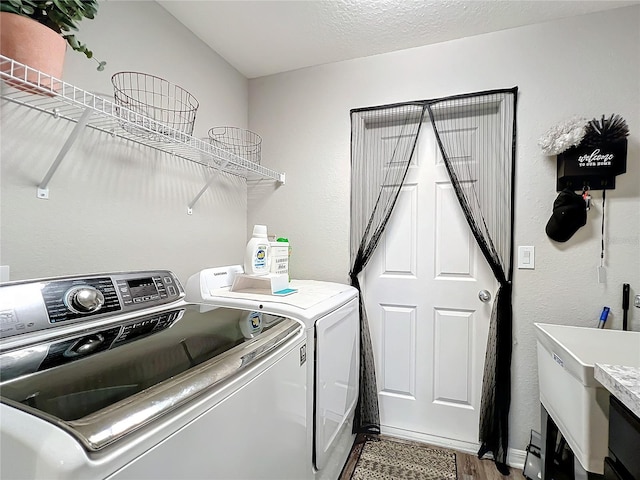 clothes washing area with wood-type flooring, a textured ceiling, and washing machine and clothes dryer