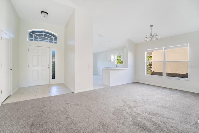 foyer with light colored carpet, vaulted ceiling, and an inviting chandelier