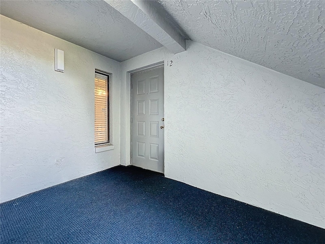 interior space with dark carpet, lofted ceiling with beams, and a textured ceiling