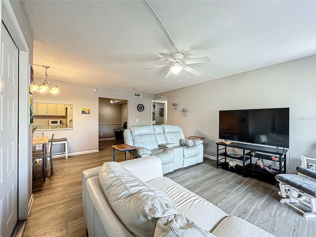 living room with a textured ceiling, hardwood / wood-style flooring, and ceiling fan with notable chandelier