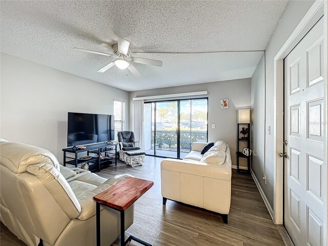 living room with a textured ceiling, dark wood-type flooring, and ceiling fan