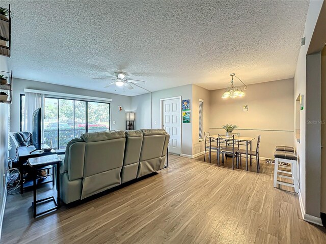 living room featuring hardwood / wood-style flooring, a textured ceiling, and ceiling fan with notable chandelier