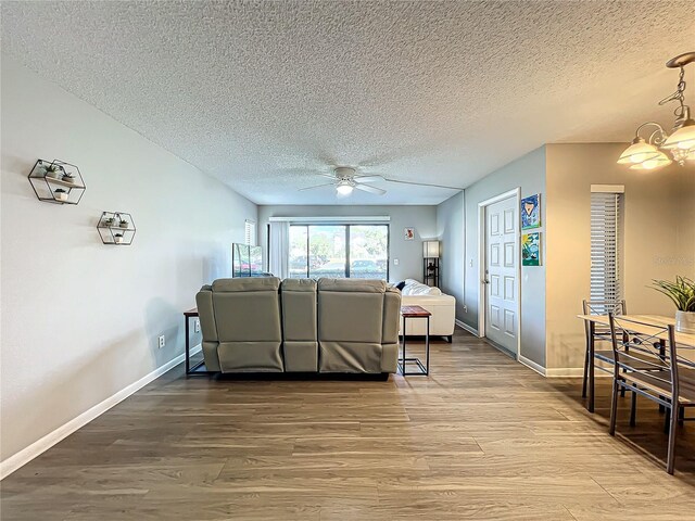 living room featuring wood-type flooring, a textured ceiling, and ceiling fan with notable chandelier