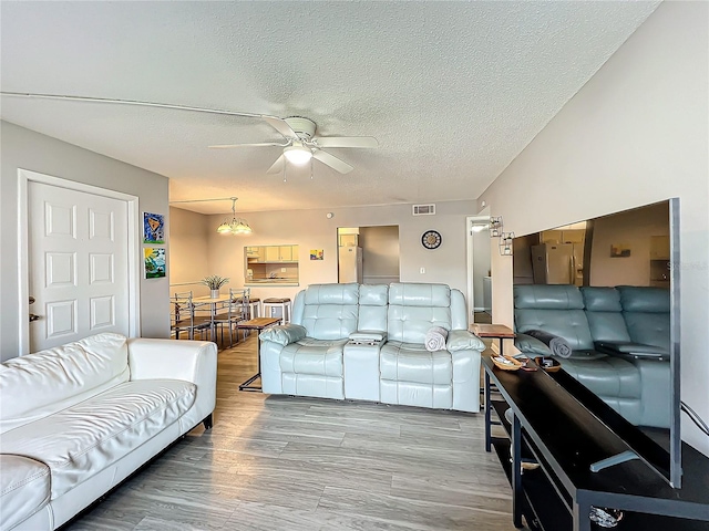 living room featuring a textured ceiling, wood-type flooring, and ceiling fan