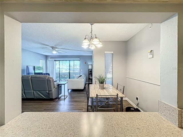 dining space with ceiling fan with notable chandelier and dark hardwood / wood-style floors