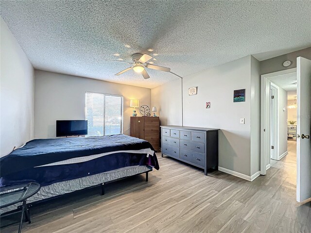 bedroom with a textured ceiling, light wood-type flooring, and ceiling fan