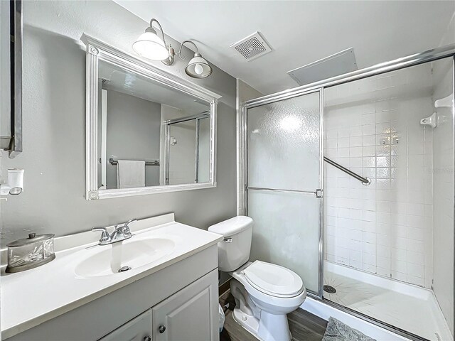 bathroom with toilet, hardwood / wood-style flooring, vanity, and a shower with door