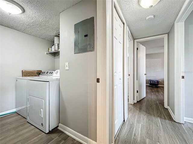 laundry room with hardwood / wood-style floors, electric panel, a textured ceiling, and separate washer and dryer