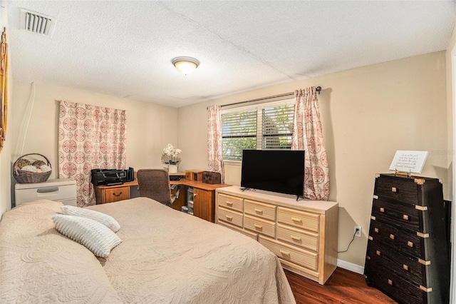 bedroom with a textured ceiling and dark hardwood / wood-style floors