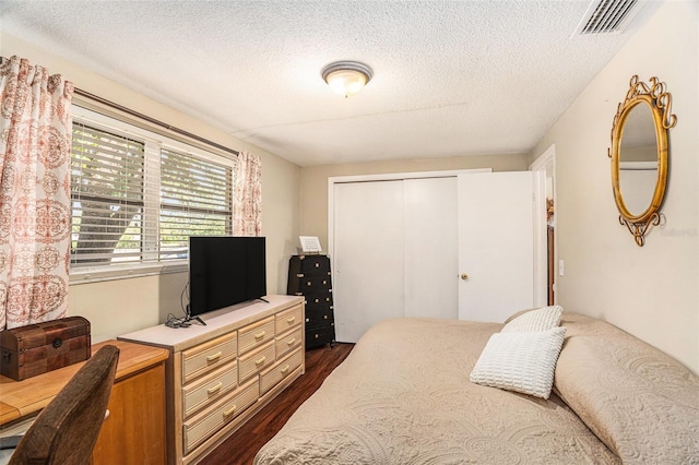 bedroom featuring dark hardwood / wood-style floors, a textured ceiling, and a closet