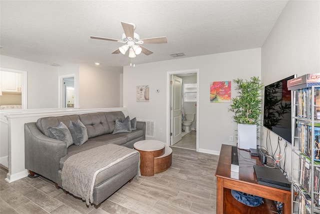 living room featuring ceiling fan, a textured ceiling, and light wood-type flooring