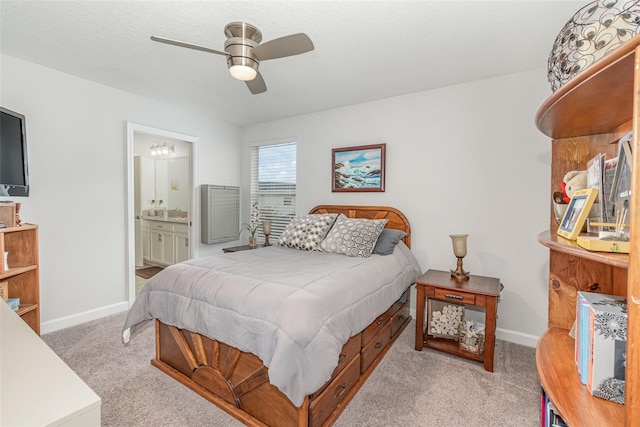 bedroom with ceiling fan, light carpet, and ensuite bath