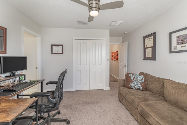 carpeted office space with ceiling fan and a textured ceiling