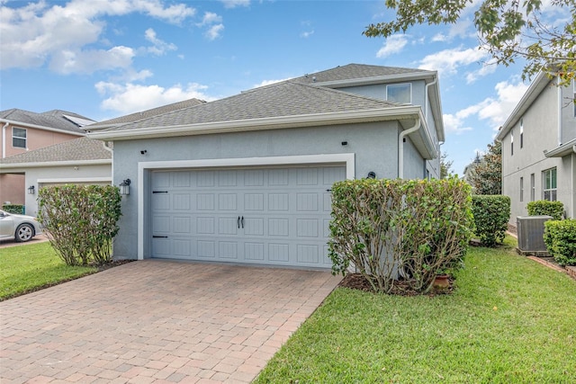 view of front of home featuring a front lawn, central AC unit, and a garage