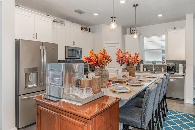 kitchen with white cabinetry, pendant lighting, and appliances with stainless steel finishes