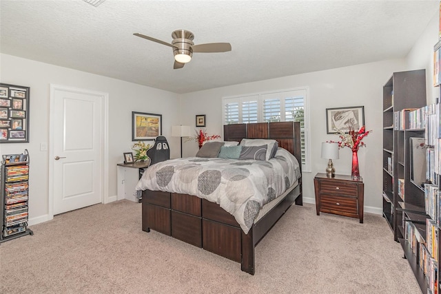 carpeted bedroom featuring ceiling fan and a textured ceiling